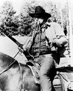 John Wayne on horseback reins in his mouth guns at ready True Grit 