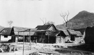 c1918 photo China  mud brick houses with thatch roofs, people in yard 