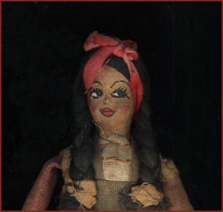   antique doll has a hand painted face and braided thread or string hair