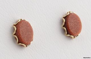  pair of earrings have scalloped borders framing oval cut goldstone